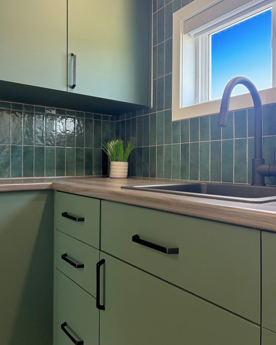 Cuisinette de bureau de thématique verte, armoirs miralis, backsplash en briques verts, poignée noirs et lavabo noir.