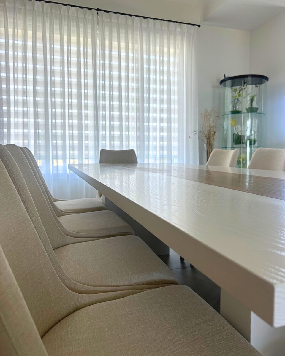 Table de la salle a manger, blanche en bois. longue avec plus places. pieces lumineuses et mdoerne. banc en tissu blanc.